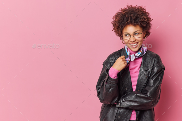 Studio shot of pretty curly haired young woman smiles happily